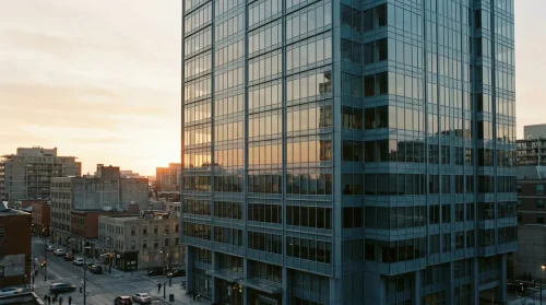 Modern office tower reflecting sunrise in a Canadian city, symbolizing professional ambition.