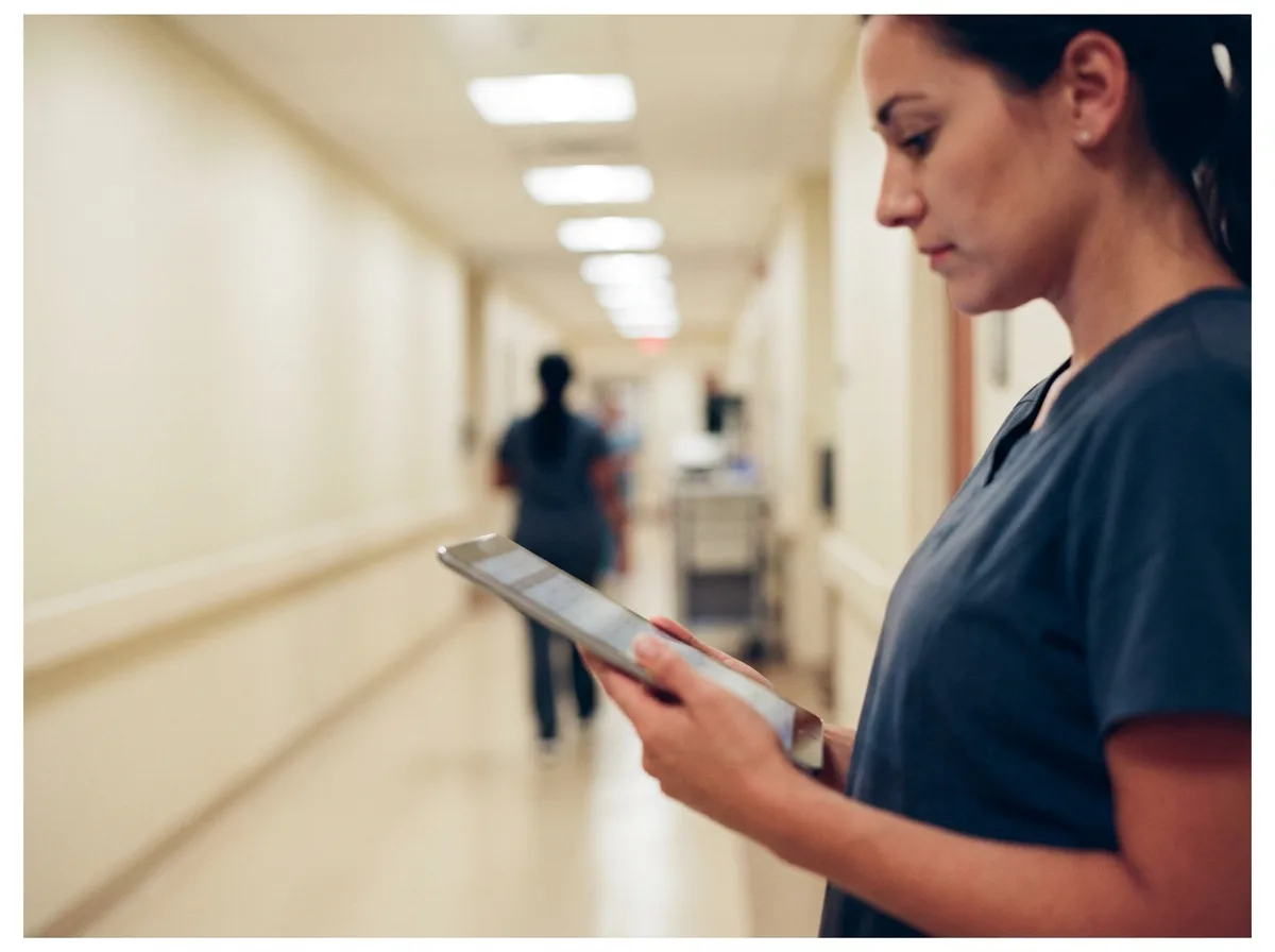Healthcare Professional in Alberta Female Registered Nurse reviewing patient chart on a tablet in a hospital corridor